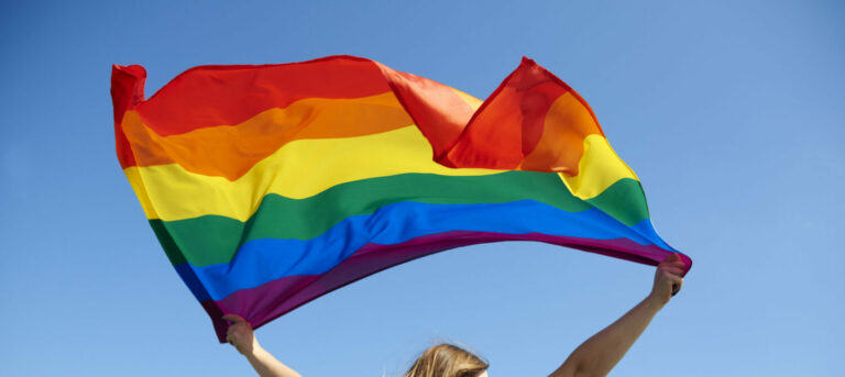 Rear view of young woman waving rainbow flag